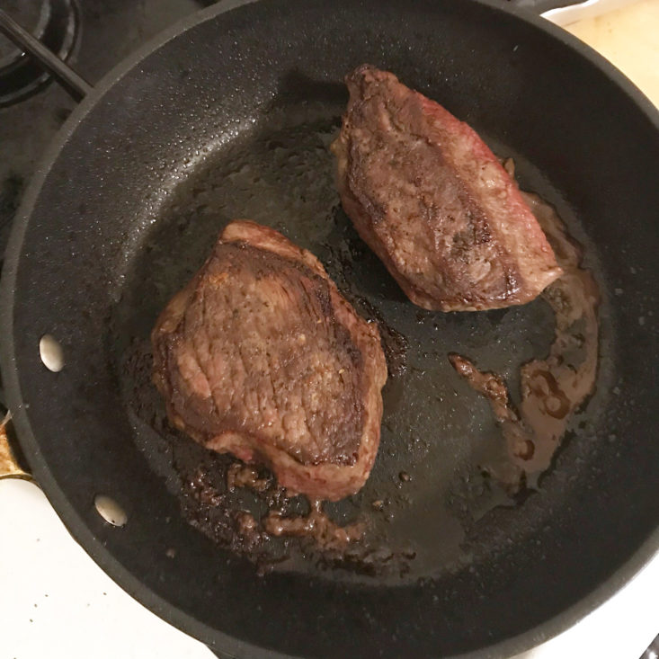 steaks cooking in pan