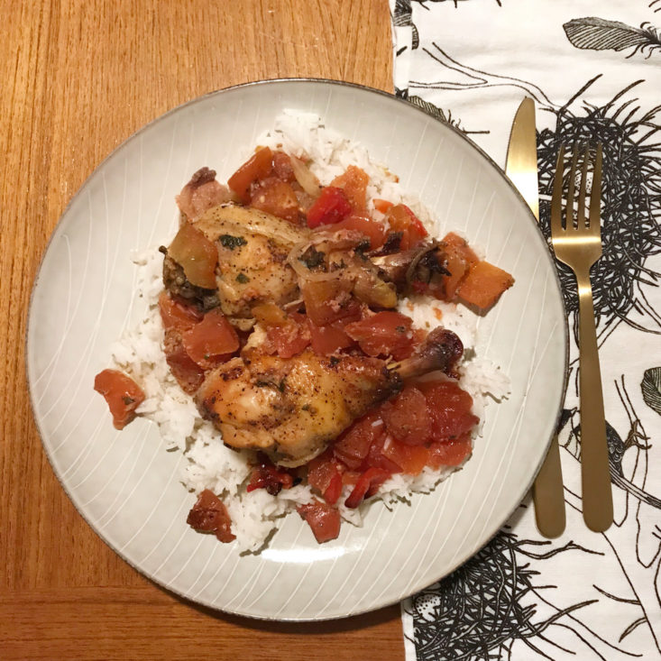 Chicken Drumsticks with Tomatoes Onions and Peppers over rice on plate
