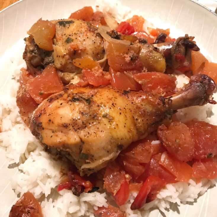 close up of Chicken Drumsticks with Tomatoes Onions and Peppers over rice on plate