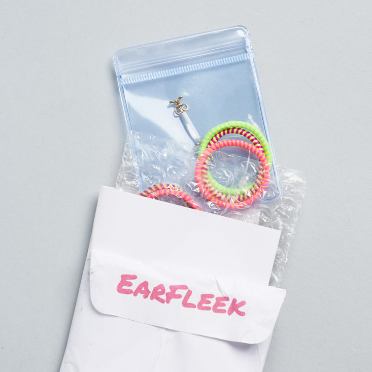 neon hair ties and a package of small butterfly earrings coming out of a paper envelope