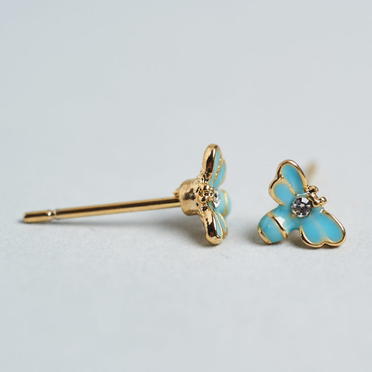 two tiny blue butterfly earrings close up, one from the front and one from the side