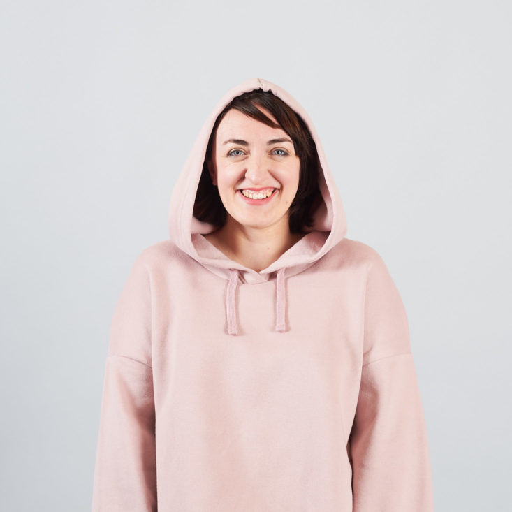 model wearing pink hoodie with hood up