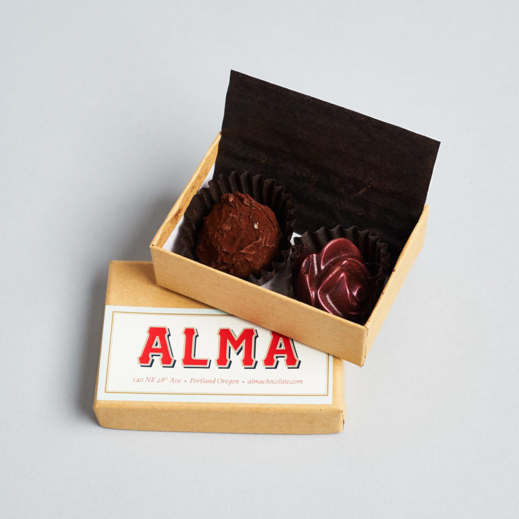 open box of alma chocolates with two chocolates inside