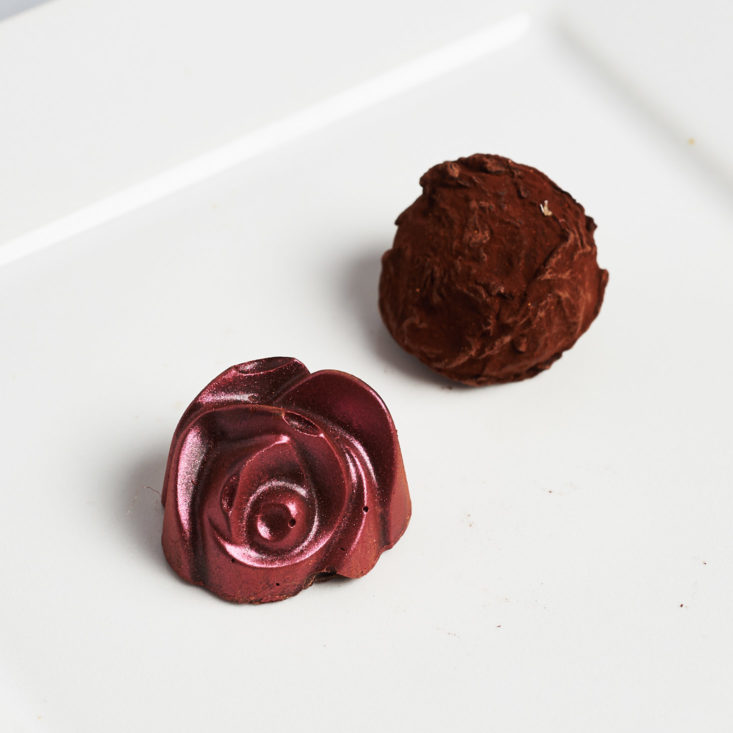 two alma chocolates, one shaped like a rose, and the other a round truffle
