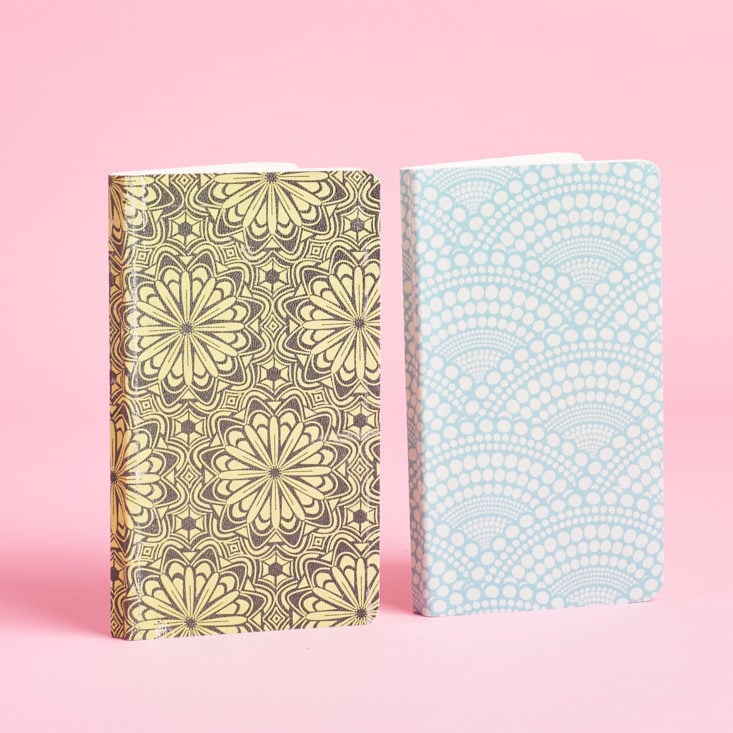 Two notebooks with patterned covers, standing on their edges.