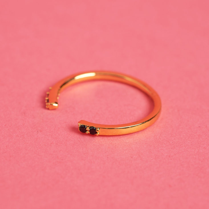 There are tiny black gems in this gold cuff-style ring from Penny + Grace