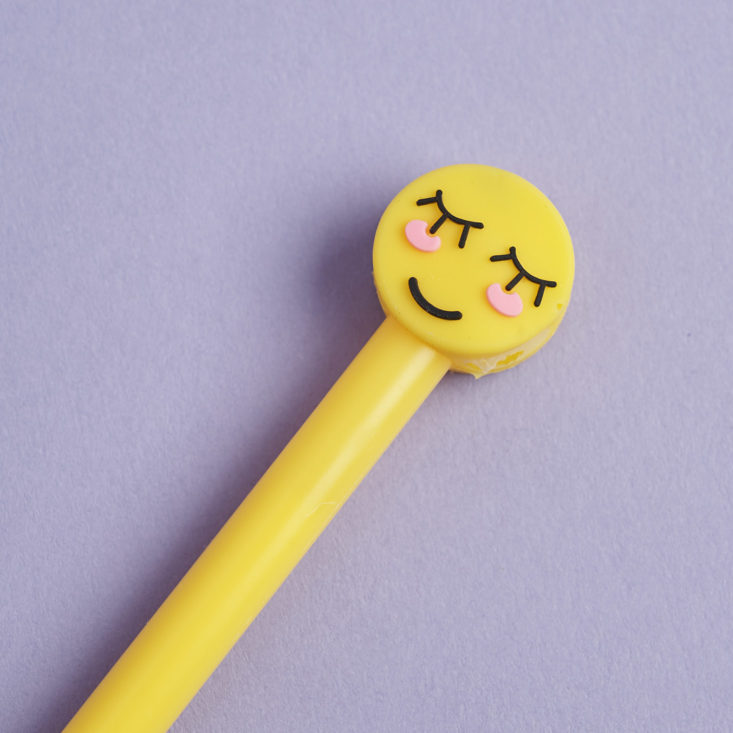 the blushing emoji cap on a yellow pen with black ink