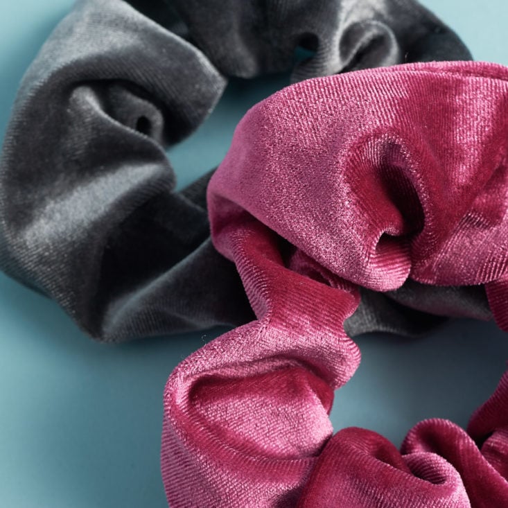 close up of two scrunchies (one maroon, and one gray) laying on top of one another