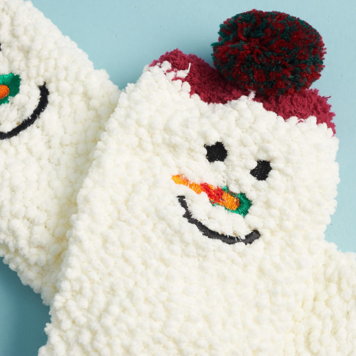 closeup of a snowman face embroidered on the ankle of a sock