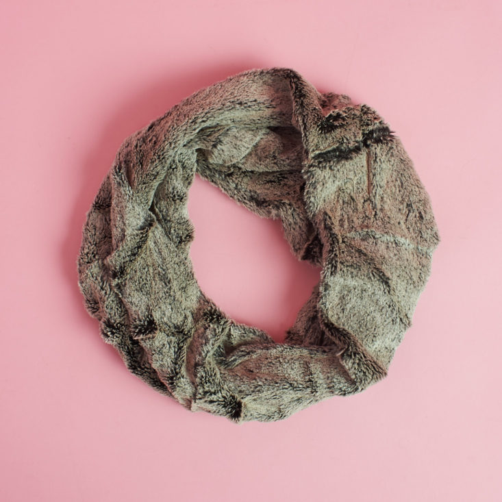 brownish furry circle scarf laying on pink table