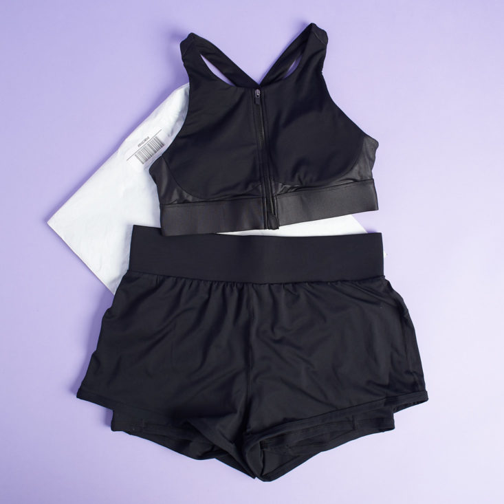 black high impact bra and running shorts from fabletics laying on white packing envelope