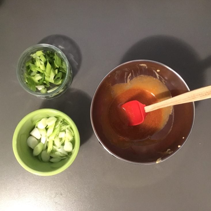 prepared egg roll in a bowl ingredients, with separated and sliced green onions, plus a mixed sauce, all mise en place