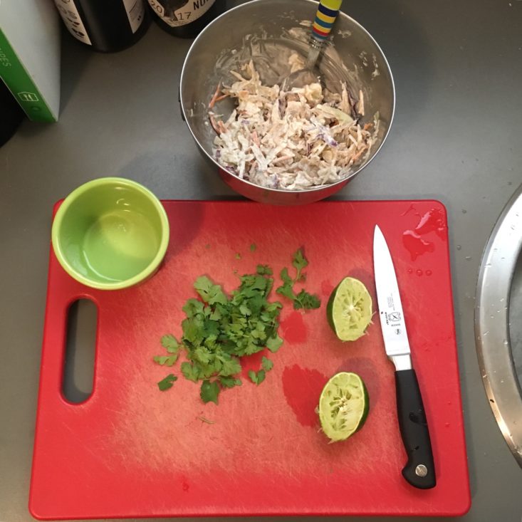 prep work for the 5-minute lunch korean BBQ chicken sandwich, including a juiced lime, a bowl of slaw mixed with mayo, and stemmed cilantro