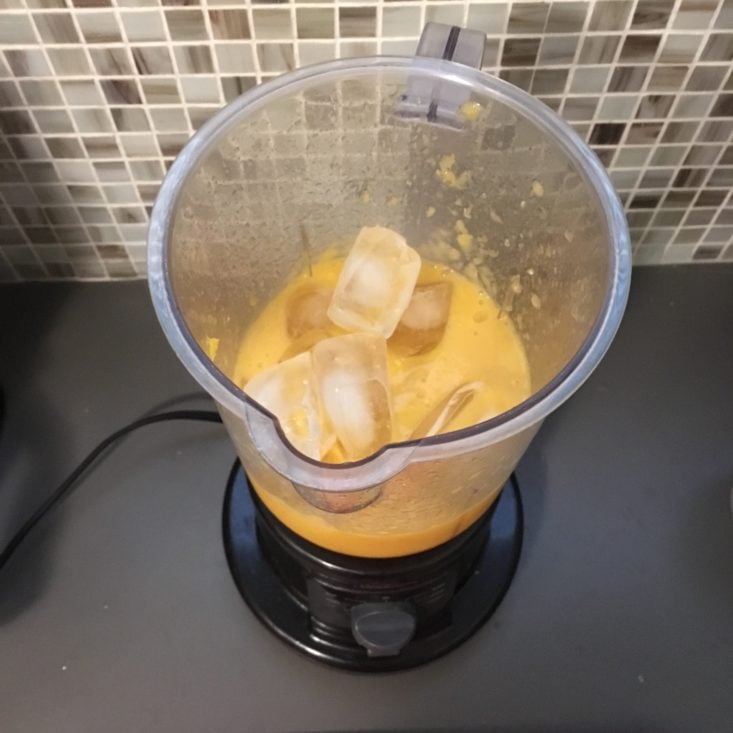 pineapple passion smoothie ingredients in the blender with unblended ice on top