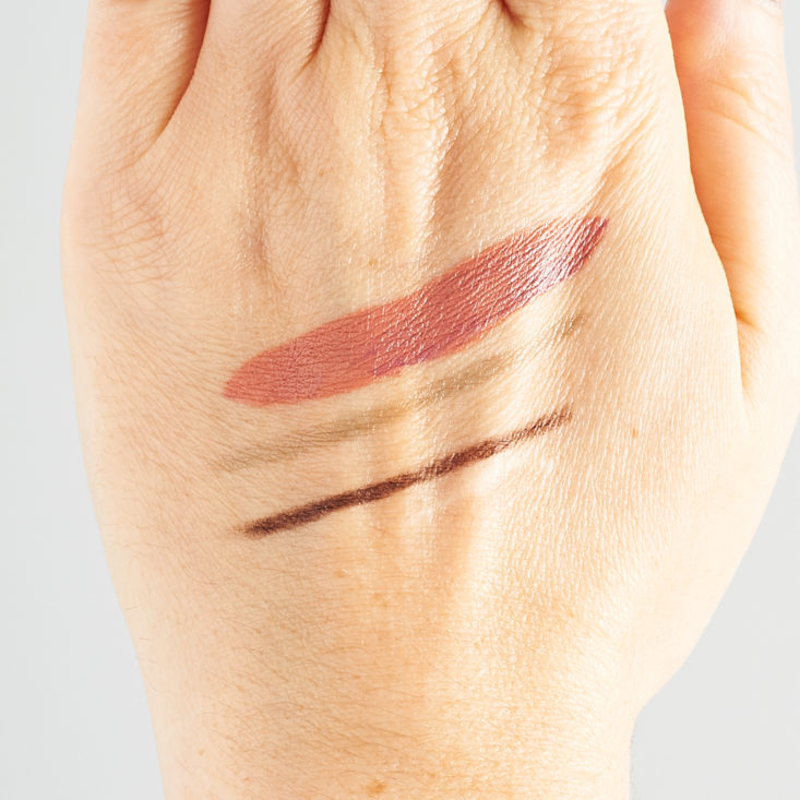 swatches of lipstick, brow liner, and eyeliner on Marne's hand
